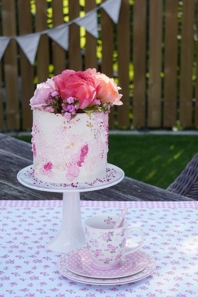 Розова торта стои върху розова покривка.