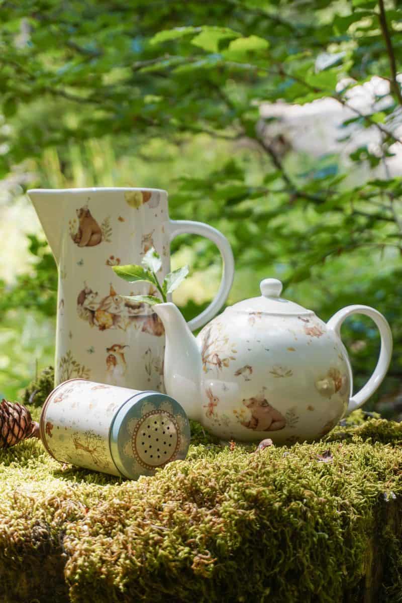 Чайник и чаша, разположени върху мъх в гората.