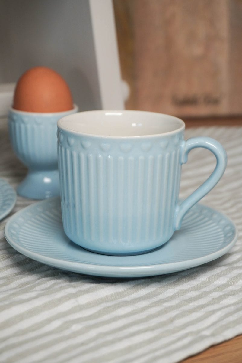 Синя чаша и чинийка на маса до яйце.