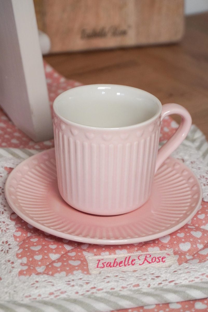 Розова чаша и чинийка върху салфетка.