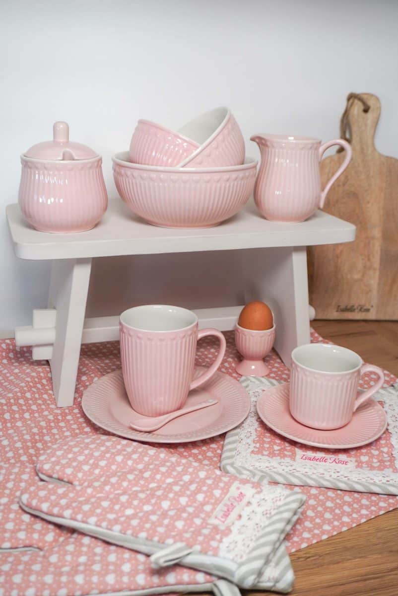 Комплект розови съдове и чаши върху дървена маса.