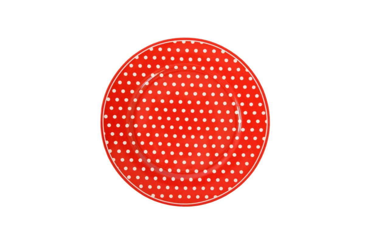 Червена чиния на точки на бял фон.